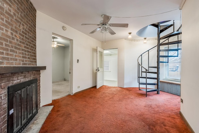 carpeted living room featuring radiator, a fireplace, stairway, and a ceiling fan