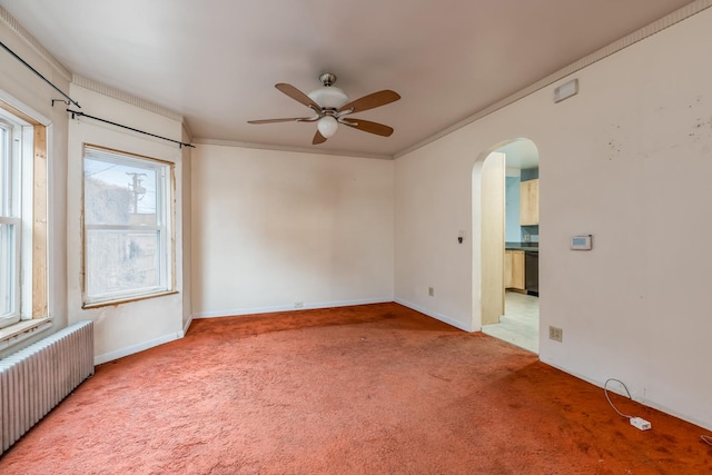 spare room with arched walkways, radiator heating unit, a ceiling fan, ornamental molding, and carpet flooring