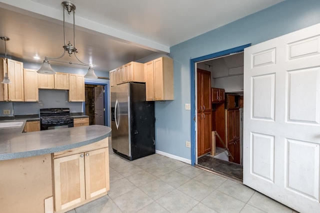 kitchen with light tile patterned floors, gas stove, light brown cabinets, and stainless steel fridge with ice dispenser