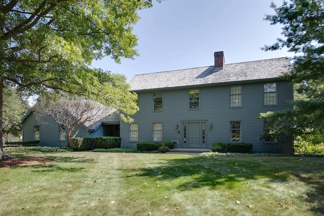 colonial home featuring a chimney and a front lawn