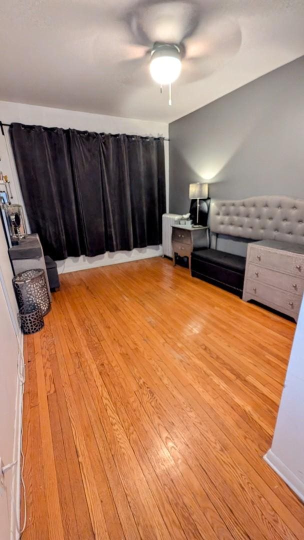 unfurnished bedroom with radiator, a ceiling fan, and hardwood / wood-style floors