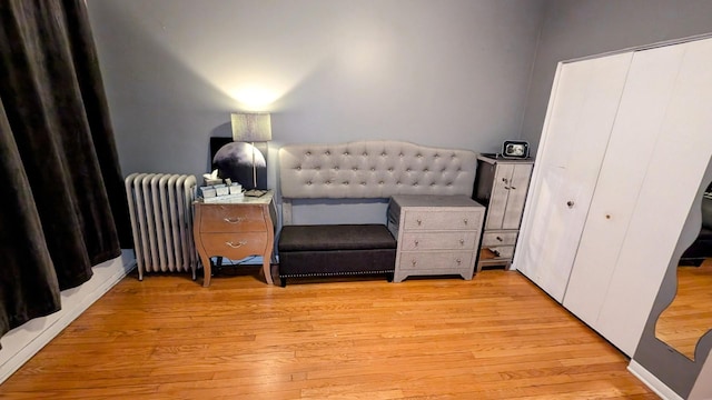 bedroom featuring a closet, light wood-style flooring, and radiator heating unit