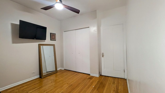 unfurnished bedroom with ceiling fan, wood finished floors, a closet, and baseboards