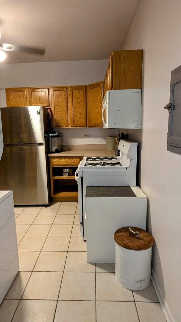 kitchen featuring white appliances, light tile patterned floors, baseboards, light countertops, and brown cabinets