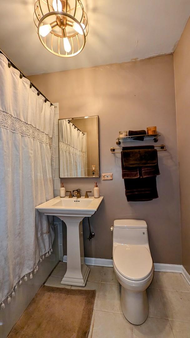 bathroom featuring tile patterned flooring, toilet, a shower with curtain, and baseboards