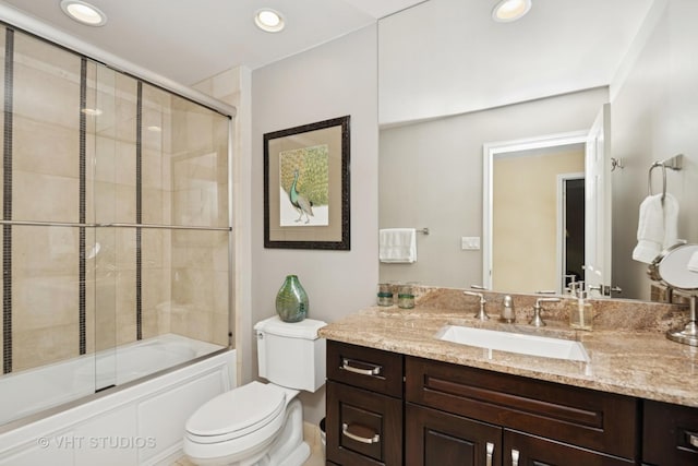 bathroom with recessed lighting, vanity, toilet, and bath / shower combo with glass door