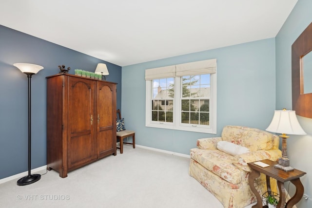 living area featuring light carpet and baseboards