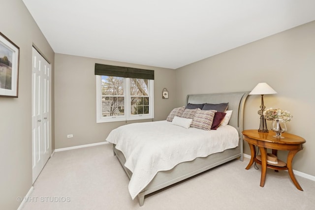 bedroom with baseboards, a closet, and light colored carpet