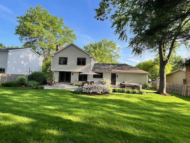 rear view of house featuring a patio area, a hot tub, fence, and a yard