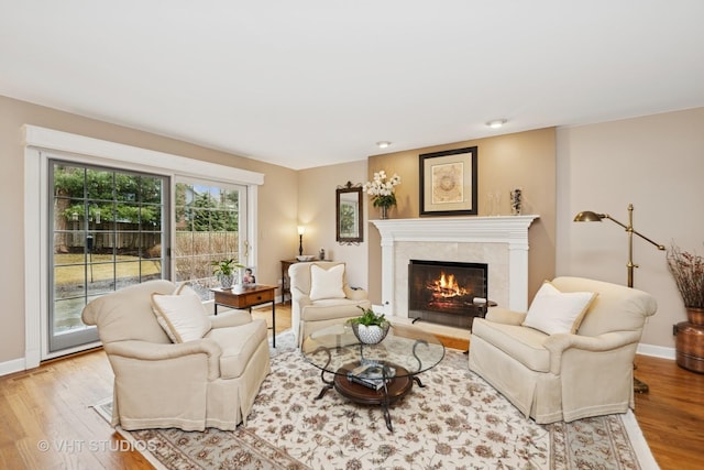 living area featuring a fireplace, baseboards, and wood finished floors