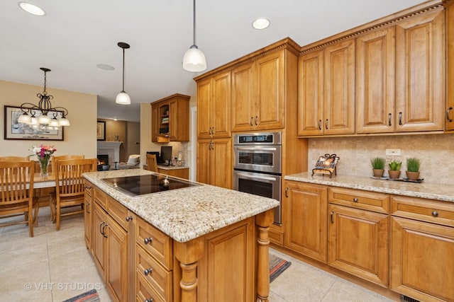 kitchen with a warm lit fireplace, double oven, black electric stovetop, backsplash, and brown cabinets