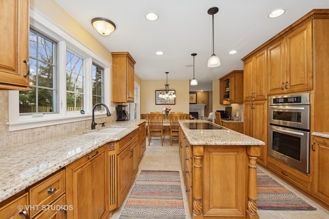 kitchen with stainless steel double oven, a sink, brown cabinetry, and a center island