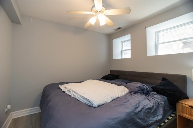 bedroom with ceiling fan, wood finished floors, visible vents, and baseboards