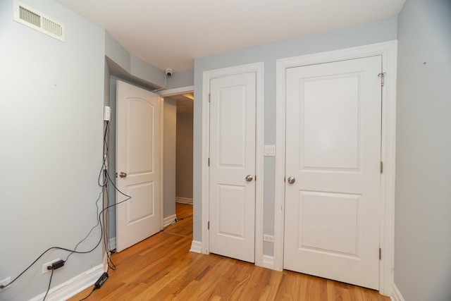 unfurnished bedroom with light wood-type flooring, visible vents, and baseboards