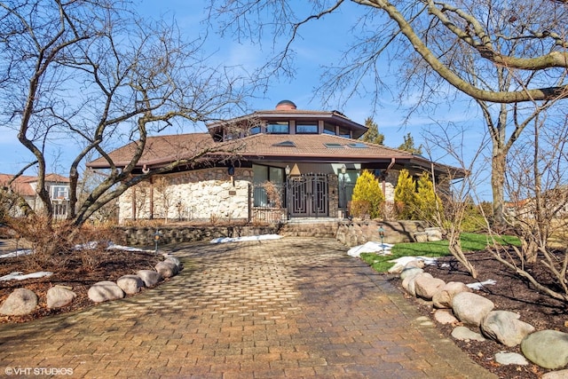 view of front of house with stone siding and a chimney