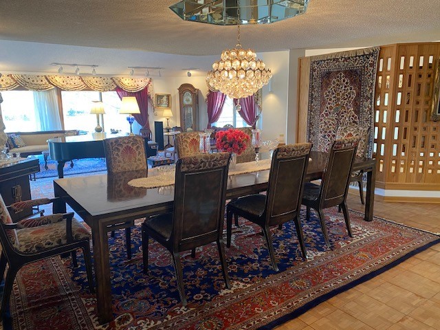 dining area featuring track lighting, a textured ceiling, and an inviting chandelier