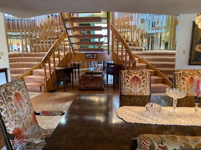 living area with tile patterned floors, a textured ceiling, and stairs