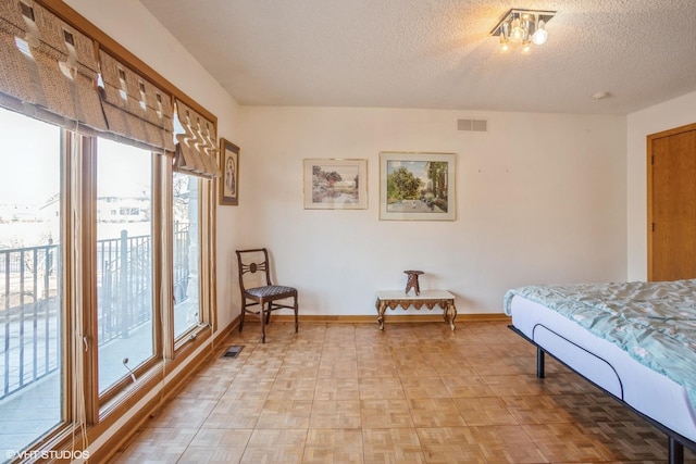 bedroom with visible vents, a textured ceiling, and baseboards