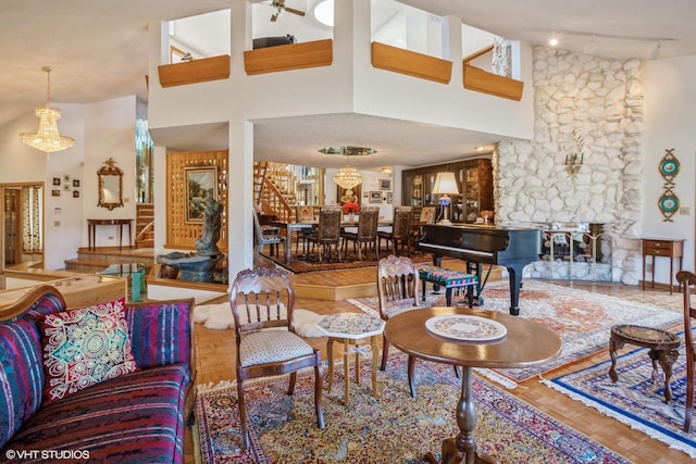 living area with track lighting, a stone fireplace, a towering ceiling, and stairs