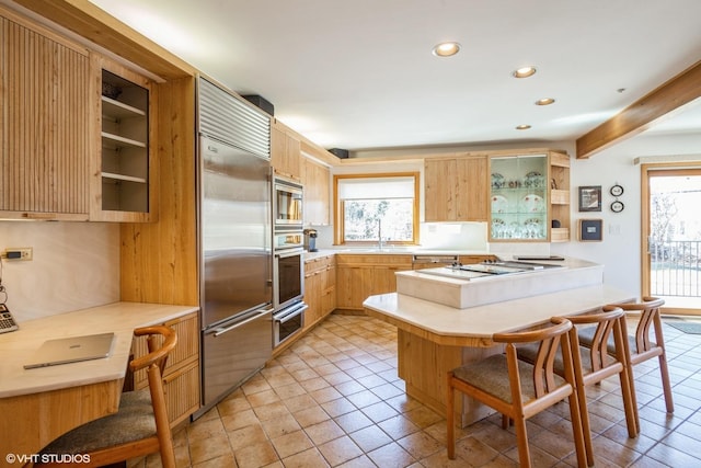 kitchen with built in appliances, a breakfast bar, light countertops, a peninsula, and open shelves