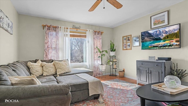 living room featuring baseboards, a ceiling fan, and wood finished floors