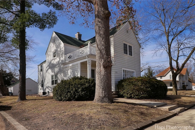 view of side of home with a balcony and a chimney