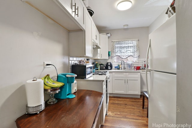 kitchen with stainless steel microwave, decorative backsplash, freestanding refrigerator, plenty of natural light, and a sink