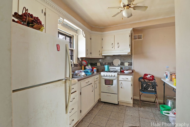 kitchen with visible vents, under cabinet range hood, dark countertops, white appliances, and decorative backsplash