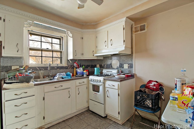 kitchen featuring visible vents, under cabinet range hood, white range with gas cooktop, decorative backsplash, and a sink