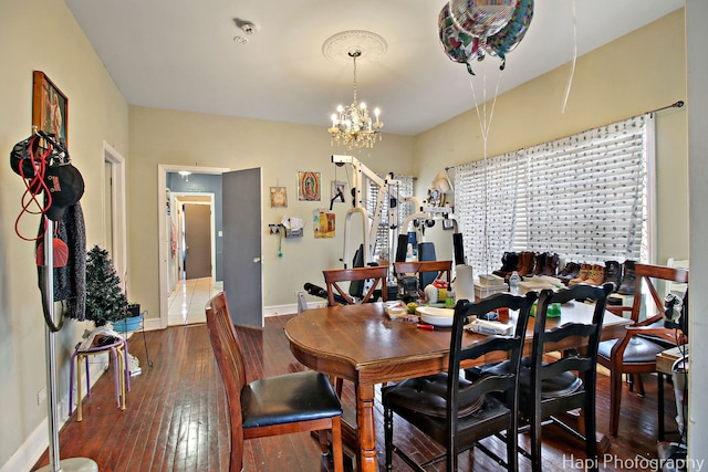 dining space with baseboards, an inviting chandelier, and hardwood / wood-style flooring