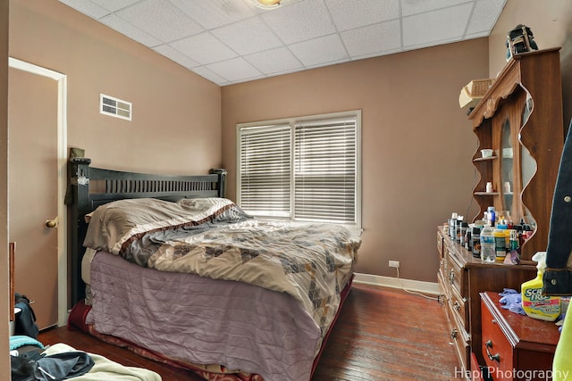 bedroom featuring a drop ceiling, baseboards, visible vents, and wood finished floors