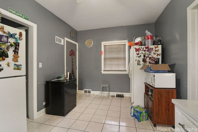 kitchen featuring white appliances, light tile patterned floors, light countertops, and visible vents