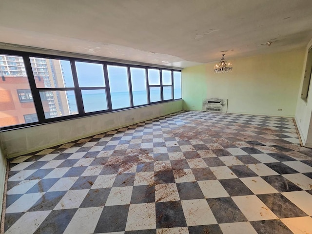 empty room featuring heating unit and a notable chandelier