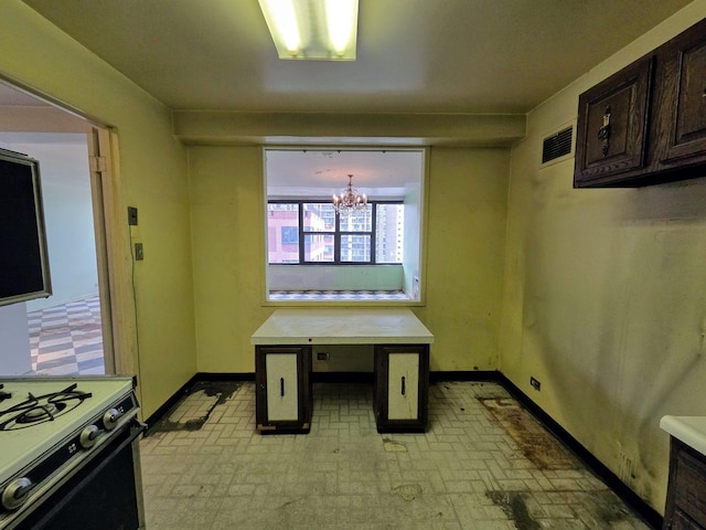 kitchen featuring visible vents, baseboards, range with gas stovetop, and a notable chandelier