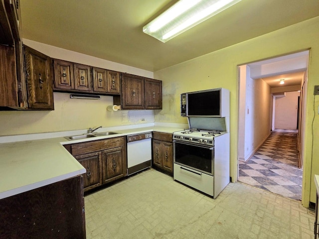 kitchen featuring dark brown cabinetry, white appliances, light countertops, light floors, and a sink