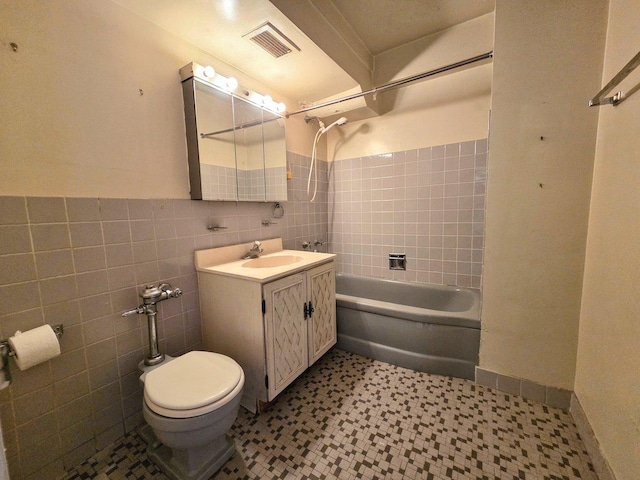 bathroom featuring visible vents, toilet, vanity, tile walls, and shower / bathing tub combination