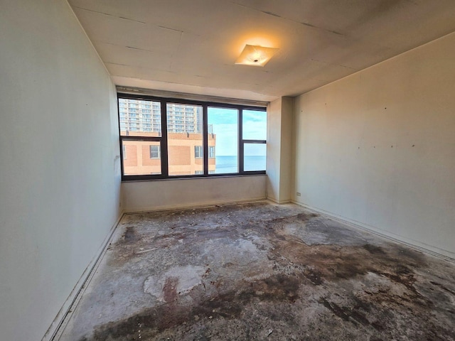 unfurnished room with baseboards and concrete flooring