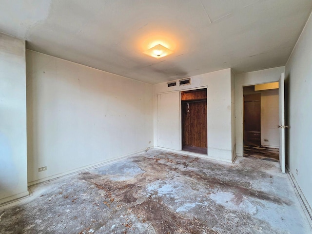 unfurnished bedroom with concrete flooring, a closet, and visible vents