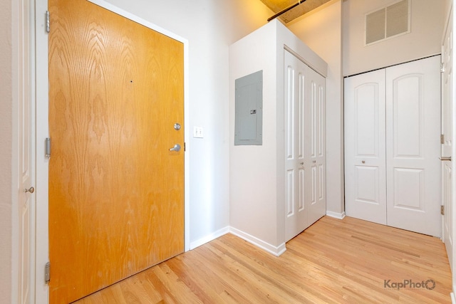 interior space with baseboards, light wood-style flooring, visible vents, and electric panel