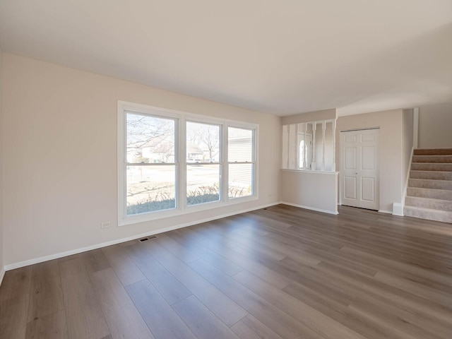 unfurnished living room with visible vents, baseboards, dark wood-type flooring, and stairs