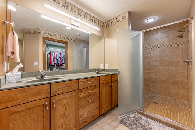 full bathroom with tile patterned flooring, a sink, a shower stall, and double vanity