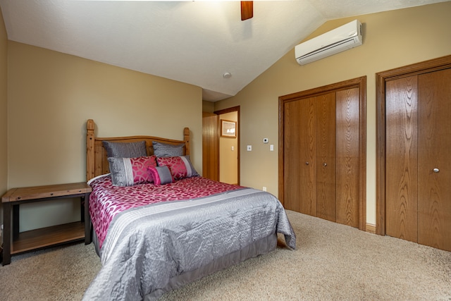 bedroom featuring carpet floors, an AC wall unit, vaulted ceiling, and two closets