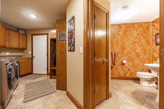 interior space featuring baseboards, brown cabinets, a textured ceiling, and washing machine and clothes dryer