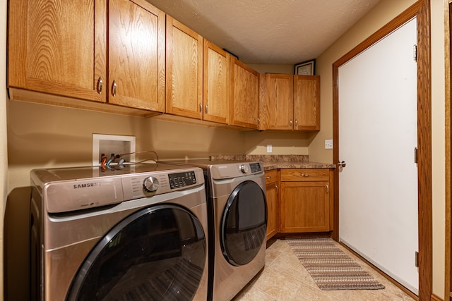 washroom with cabinet space, light tile patterned floors, baseboards, independent washer and dryer, and a textured ceiling