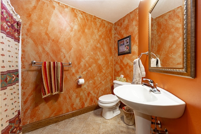 full bath with a textured ceiling, curtained shower, tile patterned flooring, toilet, and baseboards