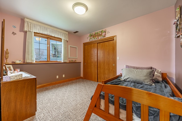 carpeted bedroom featuring baseboards and a closet