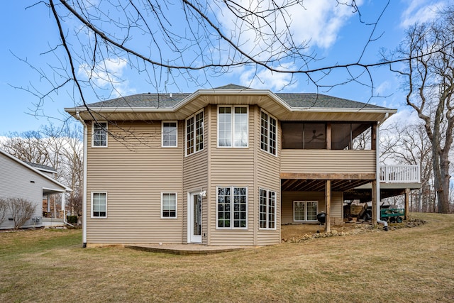 back of house with a sunroom, roof with shingles, a lawn, and a patio