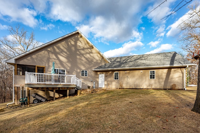 rear view of house featuring a shingled roof, a deck, and a yard