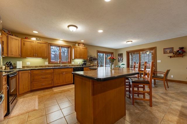 kitchen with black electric range oven, a kitchen island, a sink, and brown cabinets