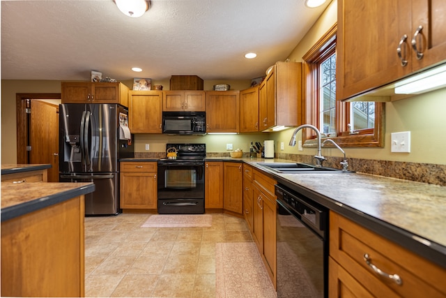 kitchen with brown cabinetry, recessed lighting, a sink, and black appliances